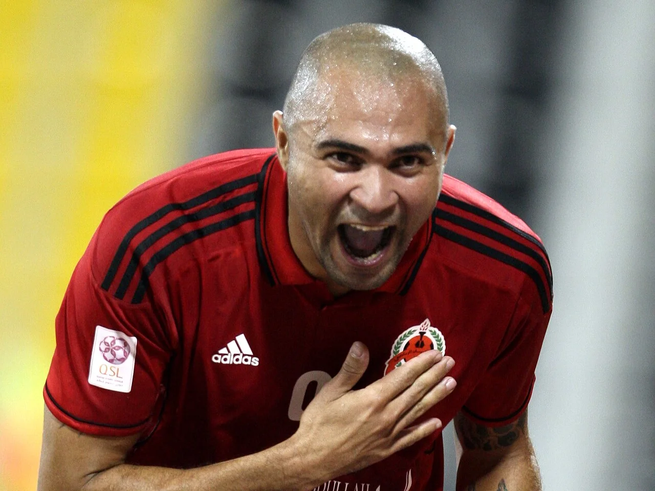 Afonso Alves i Al-Rayyans röda matchtröja jublar med handen mot klubbmärket