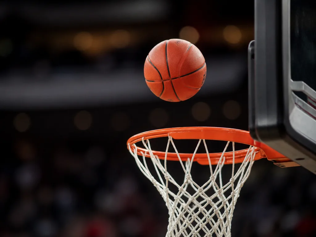 Basketboll i luften ovanför korgen under en match i en inomhusarena