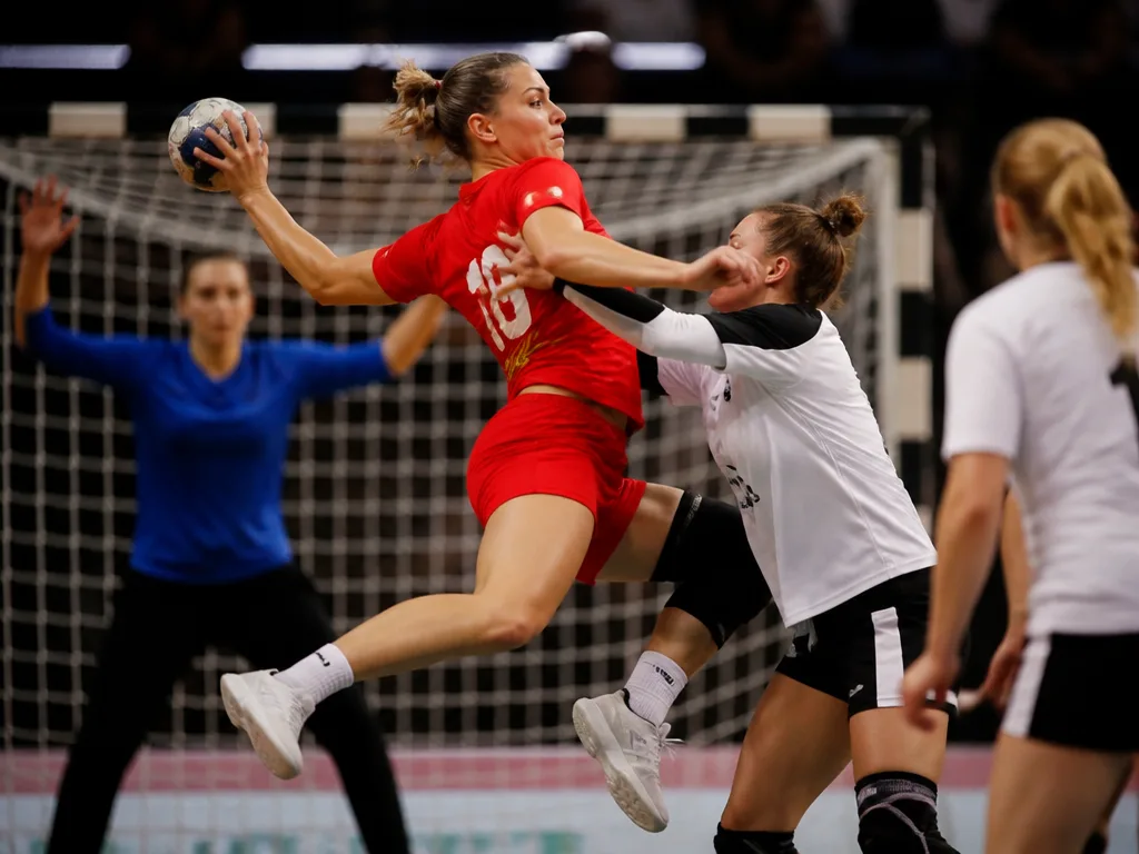 Handbollsspelare i luftduell framför mål under en match i en inomhusarena